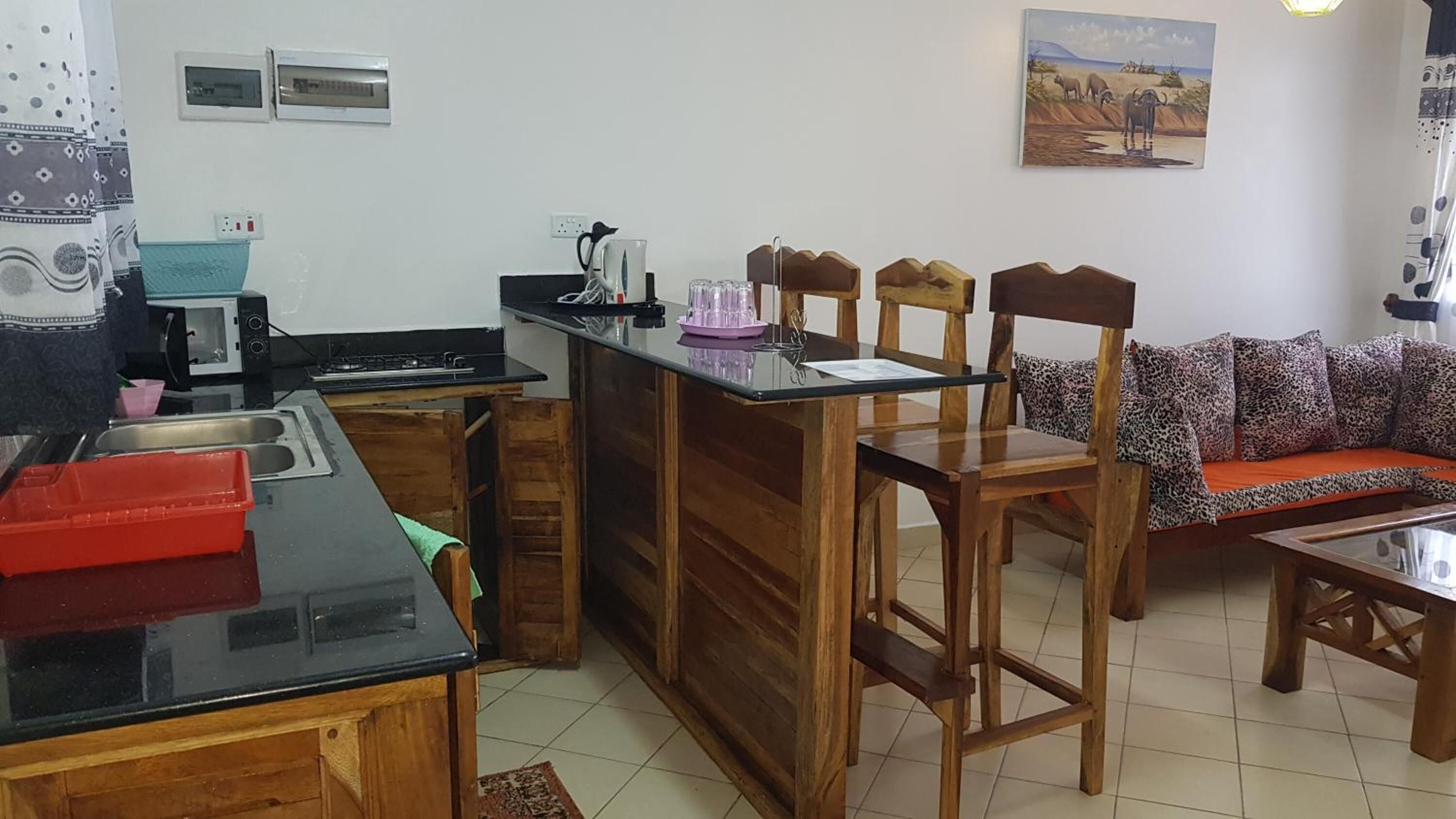 A compact living space with a kitchenette, a dining area with wooden chairs, and a sofa with patterned cushions.