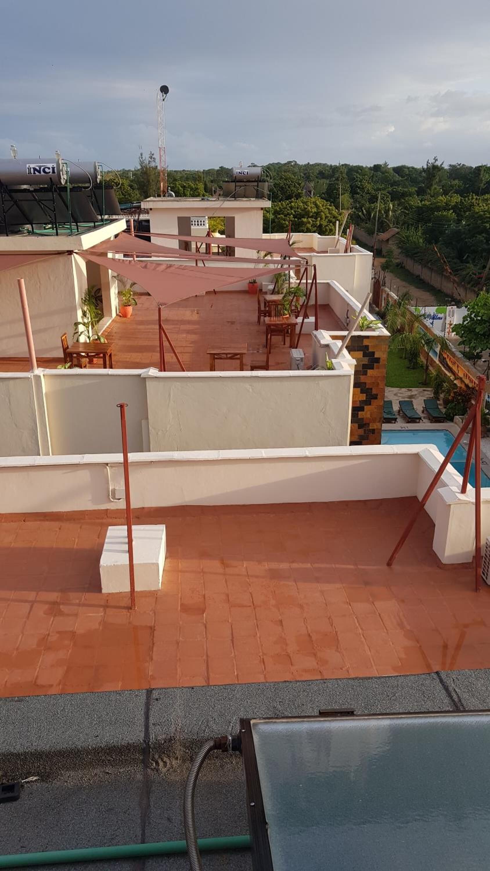 A rooftop terrace with a pool, outdoor furniture, and a view of the surrounding landscape.