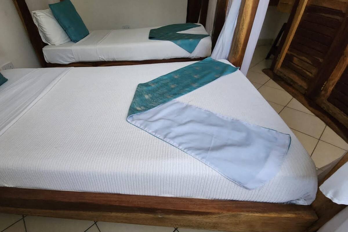 Una habitación con dos camas individuales, cada una con colchón blanco y almohadas color turquesa.