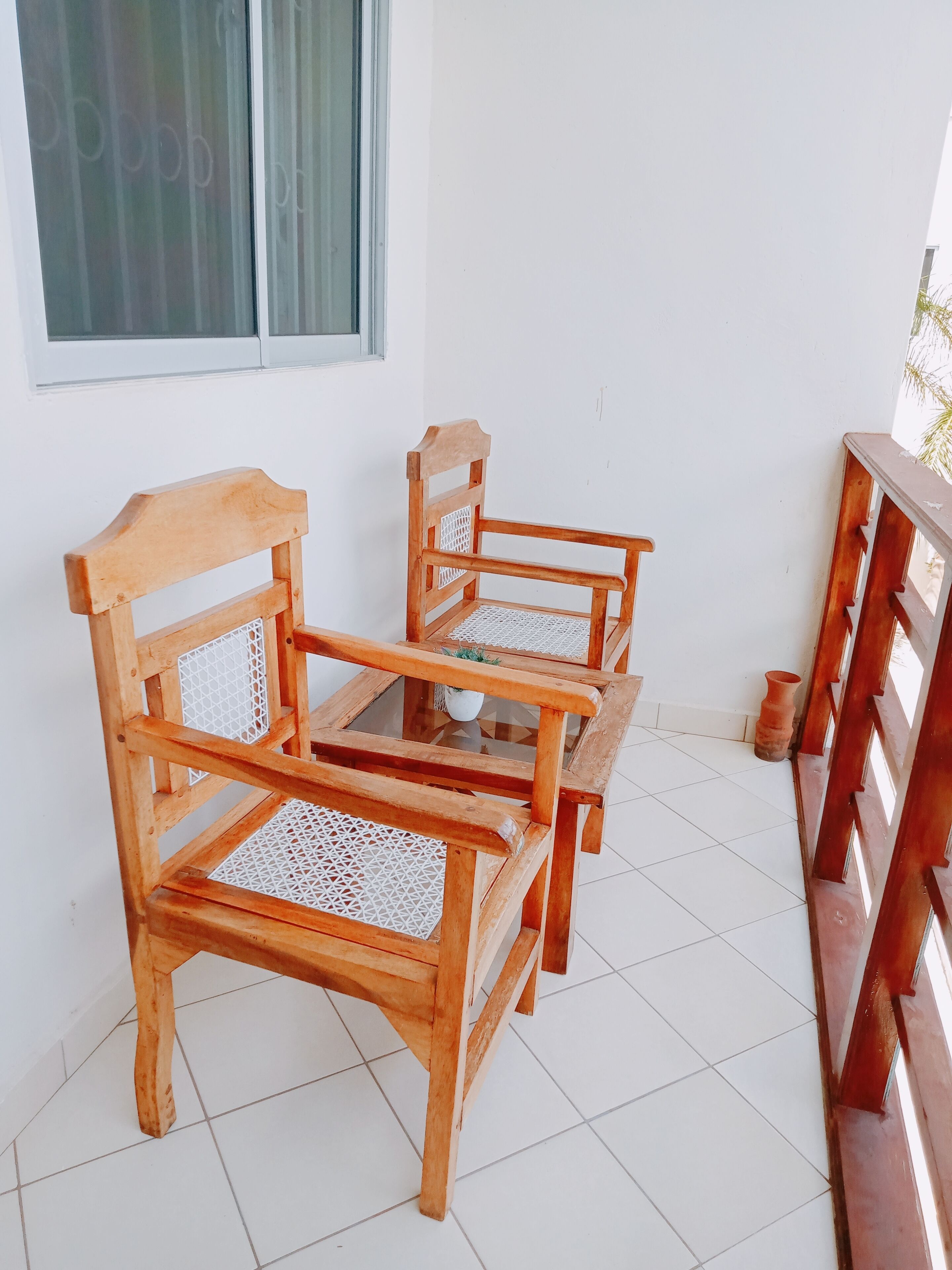 Un juego de sillas de madera con asientos y respaldos trenzados, sobre un piso de baldosas.