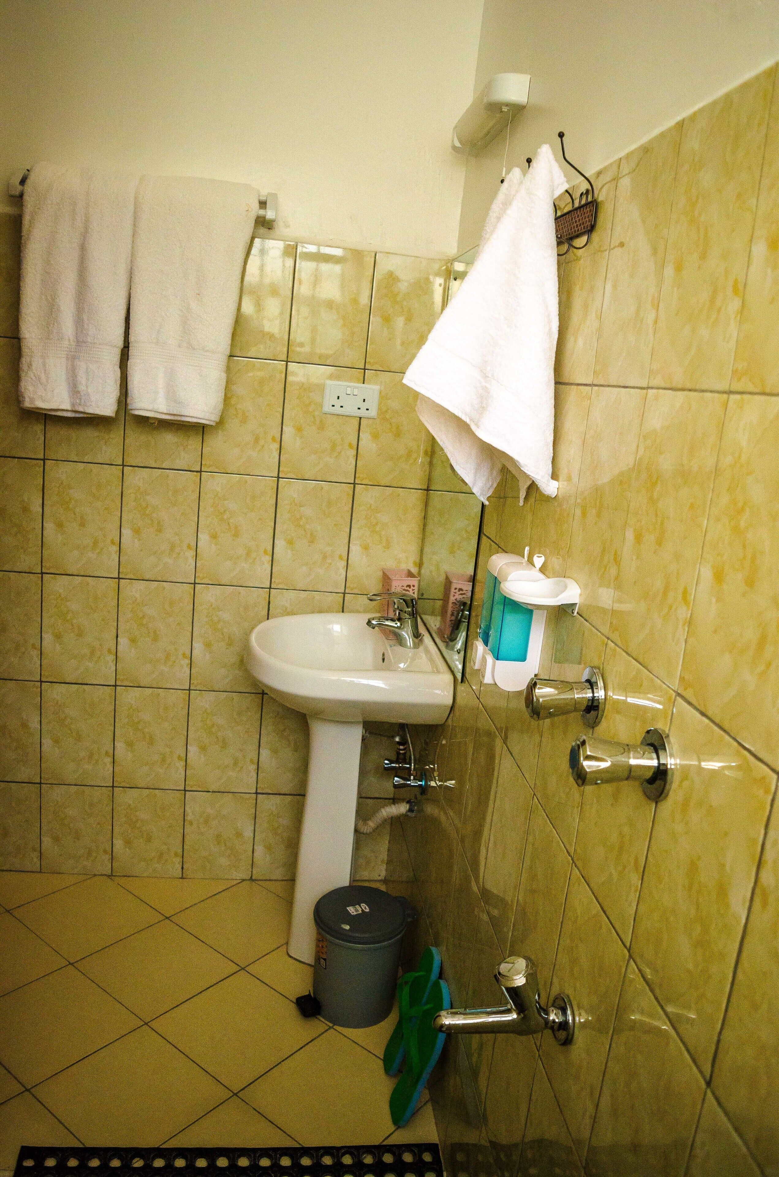A bathroom with a sink, mirror, and two towels hanging on the wall.