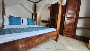 A wooden bed with a canopy, blue and white bedding, and a tiled floor. - Pendo Villas Diani (Diani Beach)