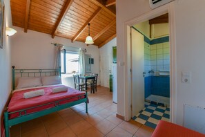 Een slaapkamer met een bed, een bureau en een badkamer met blauwe tegels.