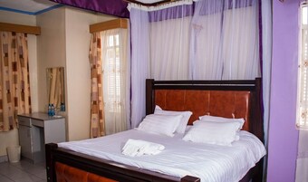 Una cama bien hecha con sábanas y almohadas blancas, un cabecero de madera y una mesita de noche con artículos de tocador.