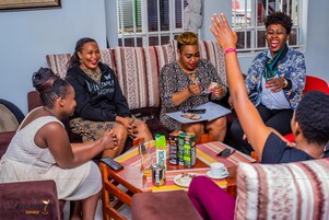Un grupo de personas sentadas en un sofá y una mesa con bebidas y aperitivos.