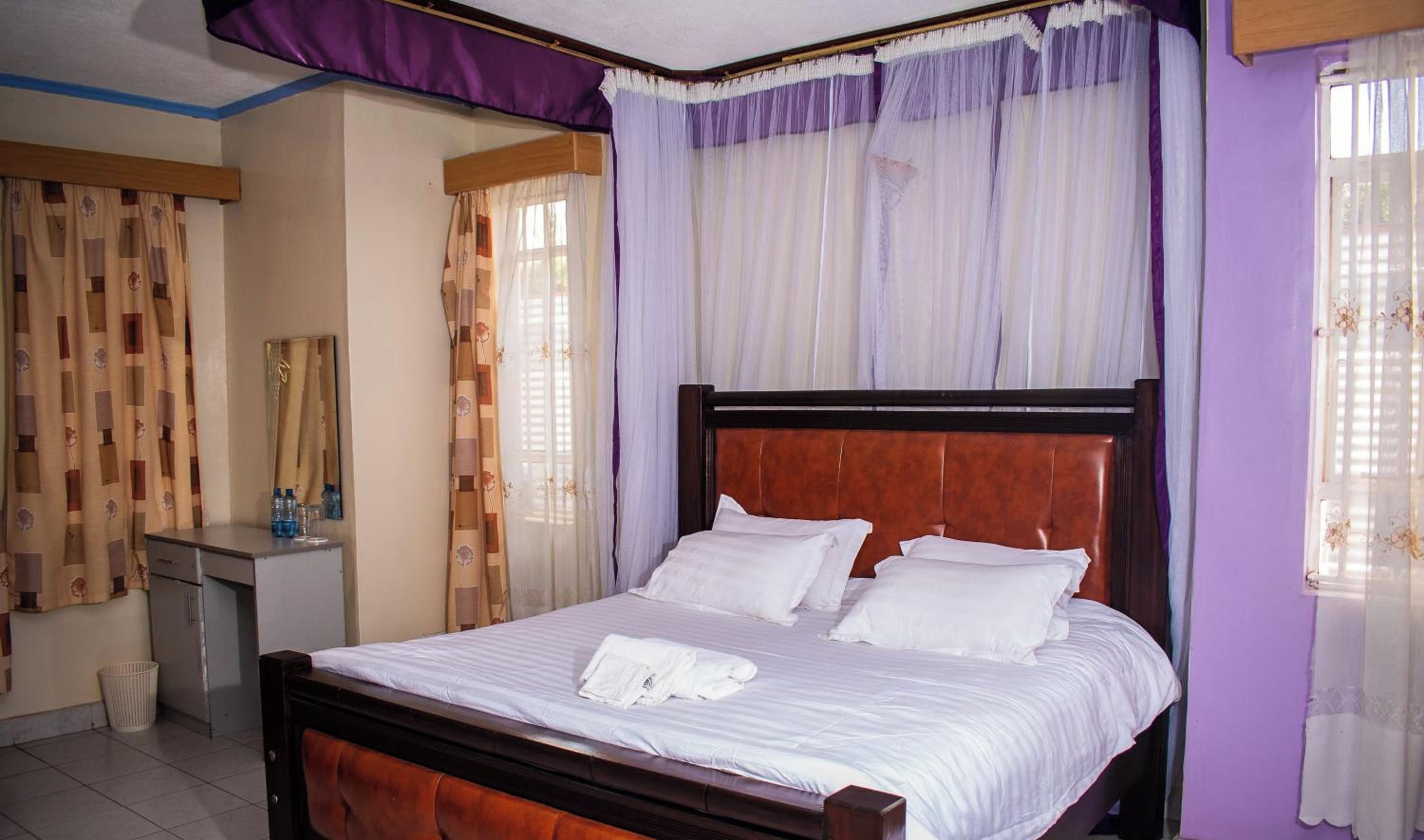 A neatly made bed with white linens, a wooden headboard, and a bedside table with a lamp.