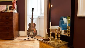 A room with a wooden dresser, a guitar, and a small brass table with candles. - JOIVY Old Town Gem - Apartment With Great City Views (Edinburgh)