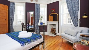 A room with a bed, a sofa, a fireplace, and a mirror. - JOIVY Old Town Gem - Apartment With Great City Views (Edinburgh)