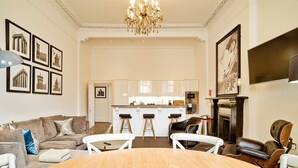 Un vaste salon avec une table à manger en bois, un canapé et une cuisine en arrière-plan.