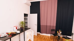 A compact kitchen with a refrigerator, a dining table with chairs, and a potted plant. - My City Apartments am Naschmarkt (Vienna)