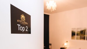 A hotel room with a bed, a nightstand, a chair, and a chandelier. There is a sign on the door that reads "My City Apartments Vienna Top 2". - My City Apartments am Naschmarkt (Vienna)