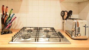 A kitchen with a gas stove, a toaster, and a utensil holder with knives. - JOIVY Gorgeous Two Bedroom Apartment With Castle Views (Edinburgh)