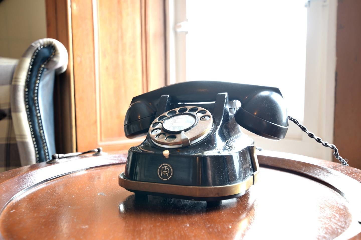 A vintage rotary dial telephone on a wooden table.