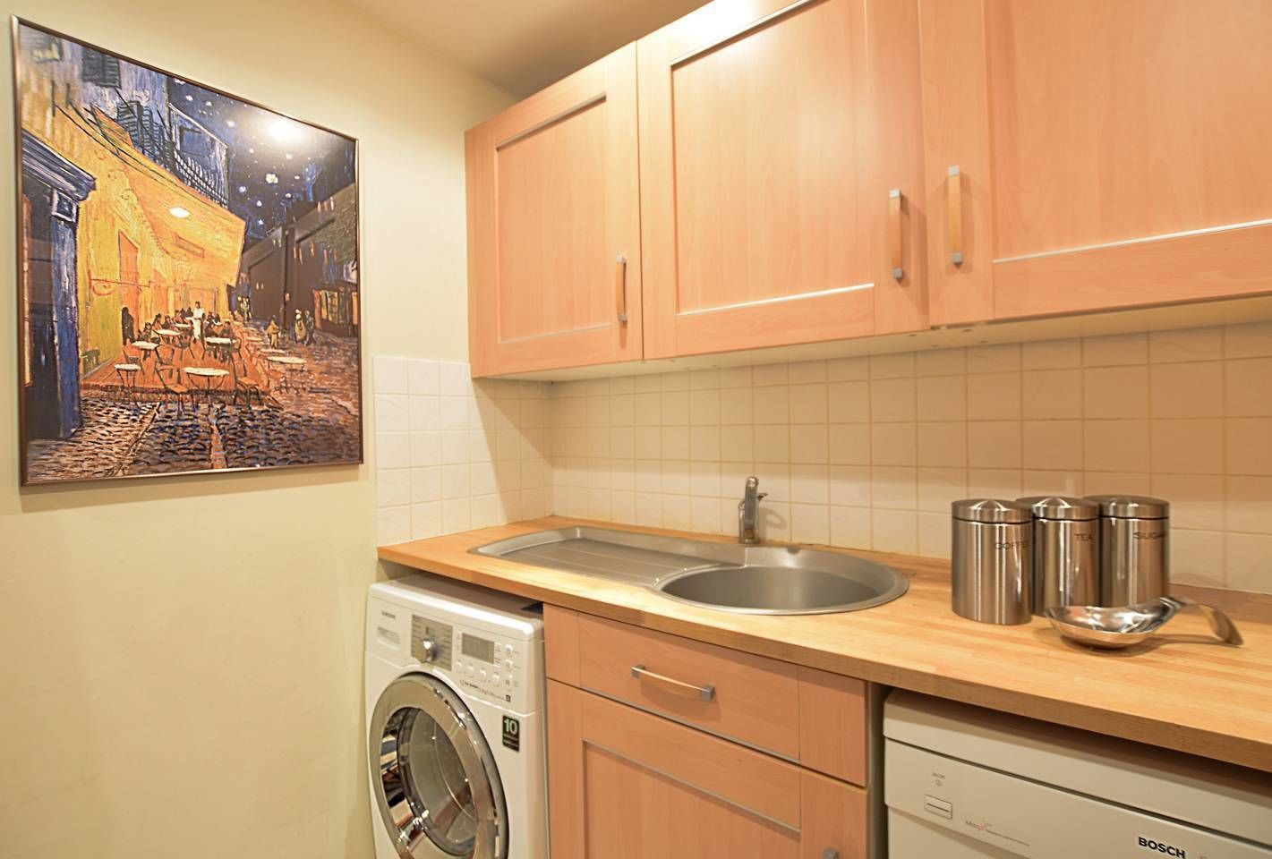 A kitchen with wooden cabinets, a stainless steel sink, a Bosch washing machine, and a Bosch dishwasher.
