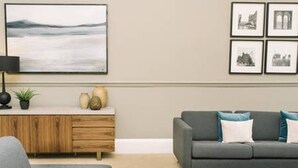 A living room with a grey sofa, a wooden sideboard, and a framed landscape painting. - JOIVY Palmerston Place Residence: Luxury City Centre Apt With Private Parking (Edinburgh)
