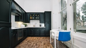 A modern kitchen with dark cabinetry, a white countertop, and a wooden floor. - JOIVY Palmerston Place Residence: Luxury City Centre Apt With Private Parking (Edinburgh)