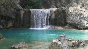 Una cascata che si getta in una piscina cristallina di colore turchese, circondata da rocce e vegetazione.