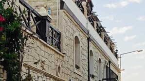 Un bâtiment en pierre doté d’un balcon, de fenêtres en arc de cercle et d’une petite entrée de boutique.