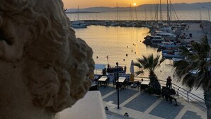 Un port de plaisance avec des bateaux amarrés, un coucher de soleil en arrière-plan et une statue au premier plan.
