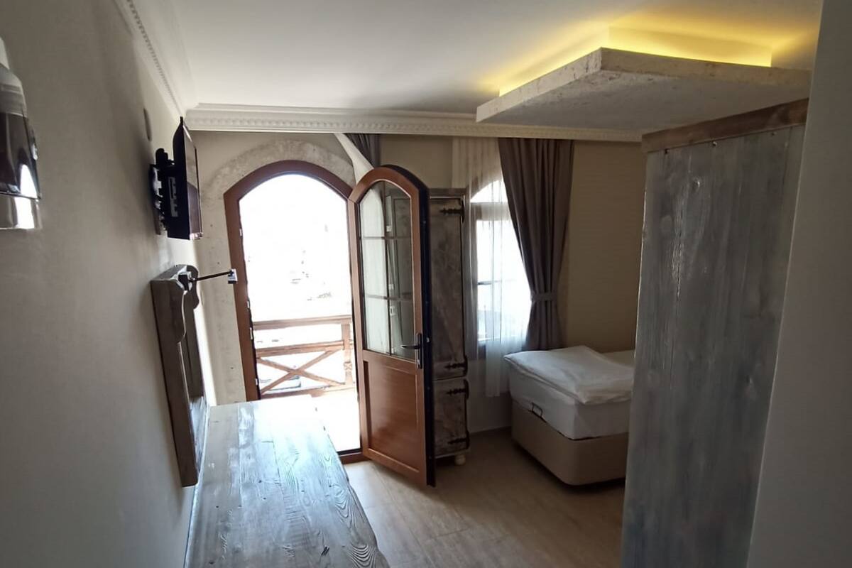 A room with a wooden table, a bed, a wardrobe, and a large mirror.