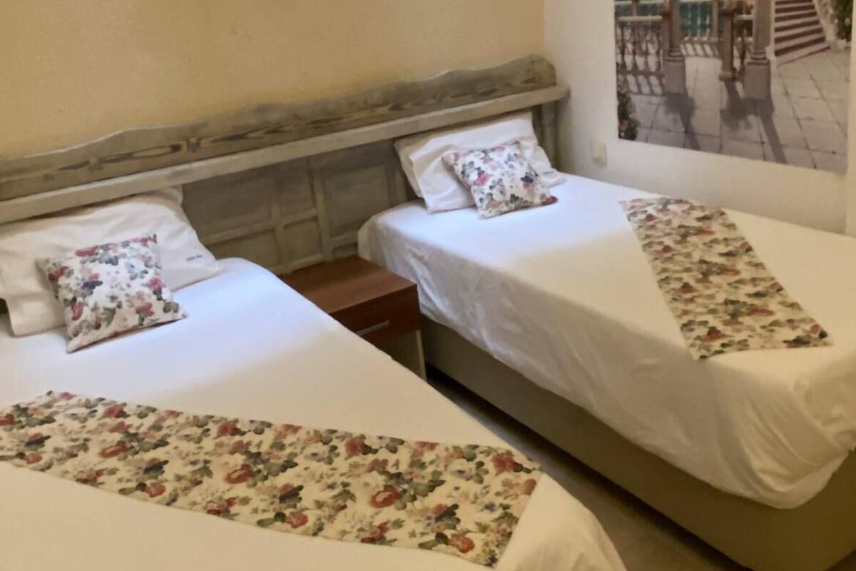 A hotel room with two beds, each with floral bedding and a view of a painted balcony.