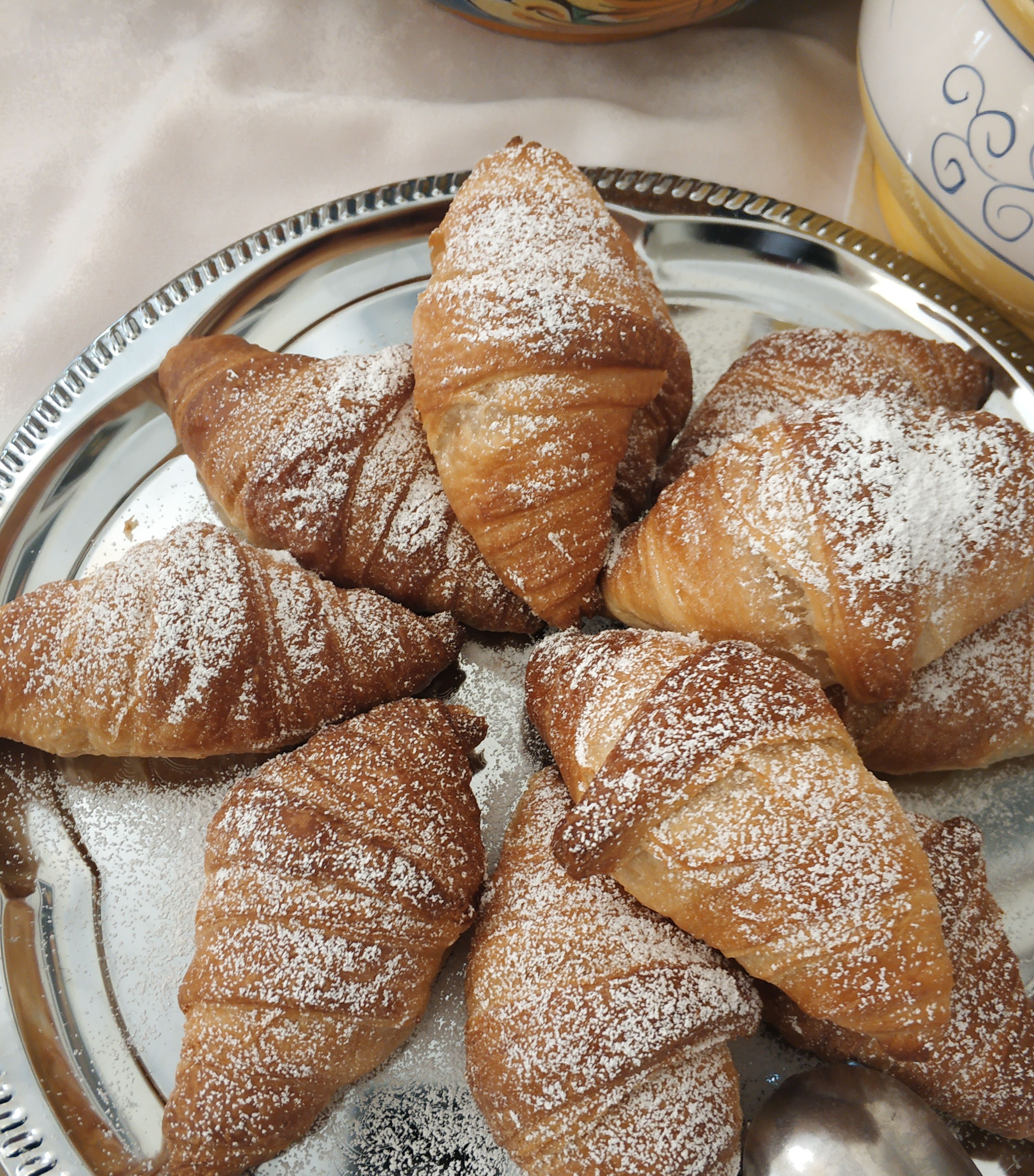 A silver tray with several pastries dusted with powdered sugar.