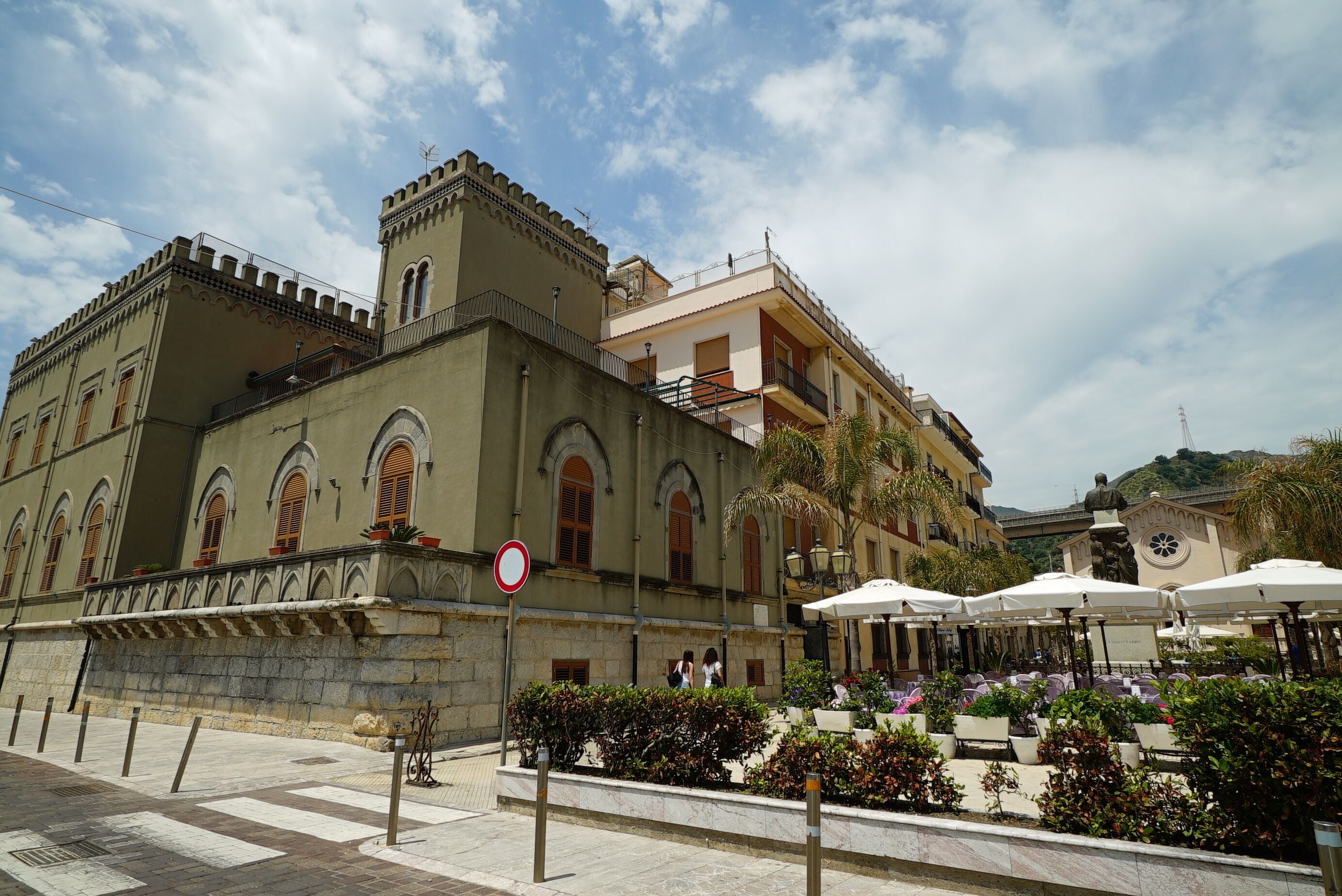 A historic building with a courtyard, outdoor seating, and a statue.