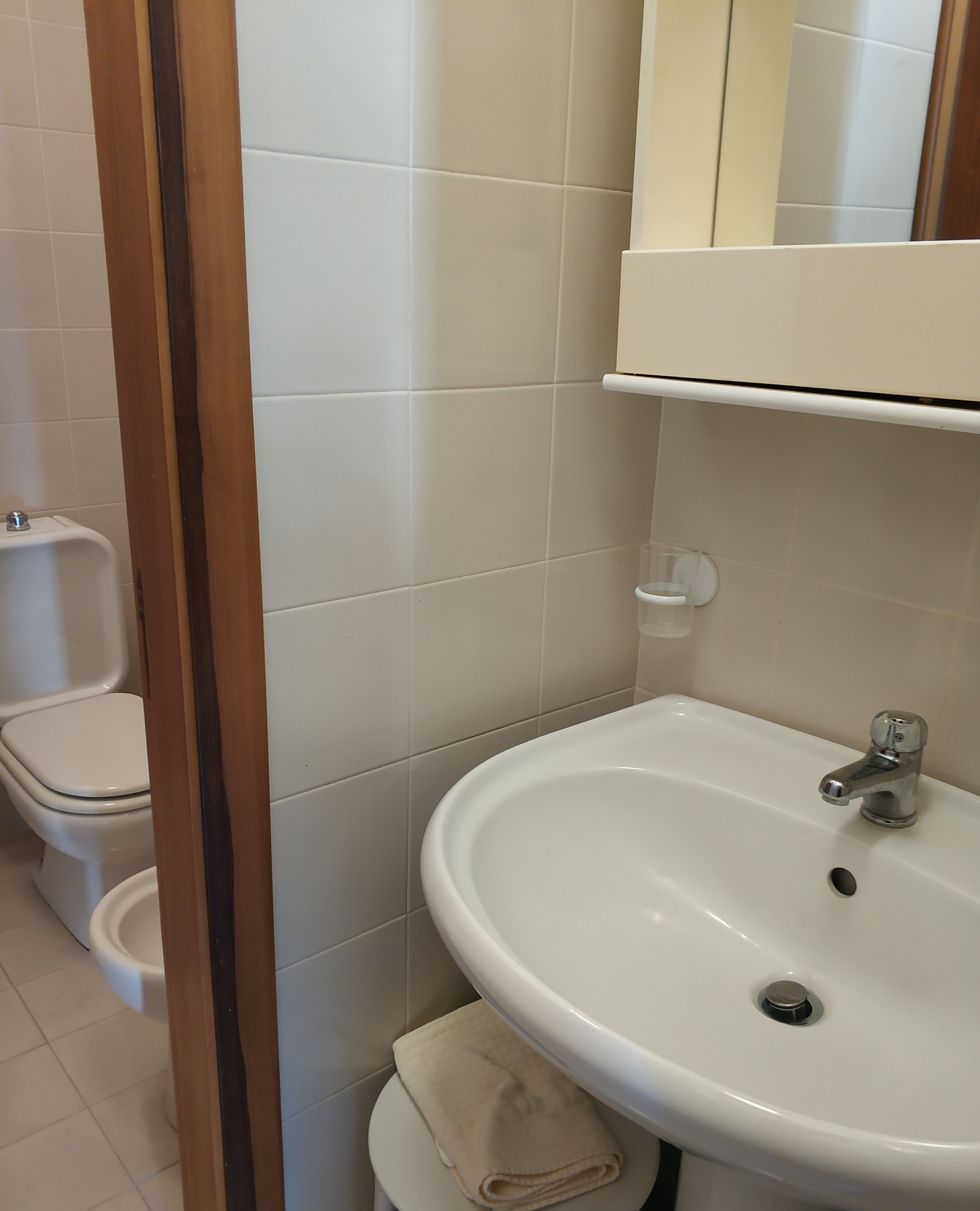 Een badkamer met een witte wastafel, toilet en een spiegel boven de wastafel.