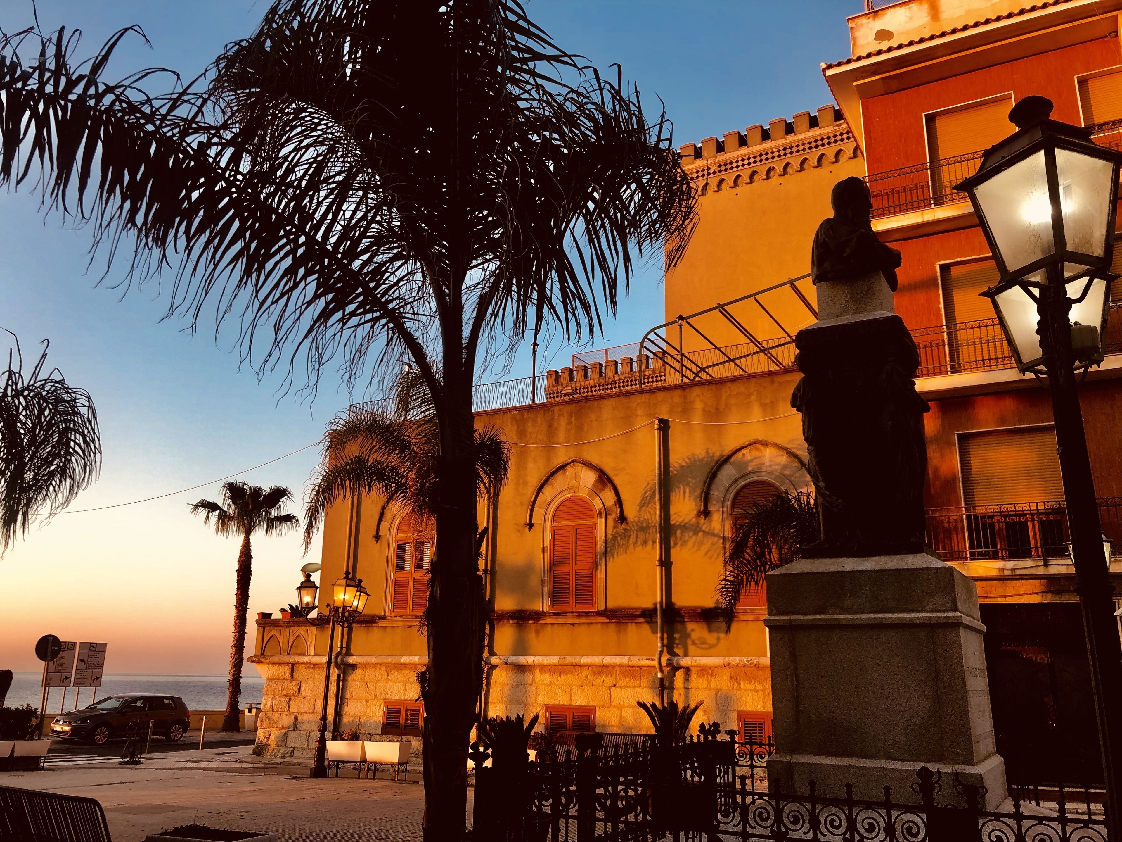 Un edificio histórico con ventanas de arco y una estatua al frente.
