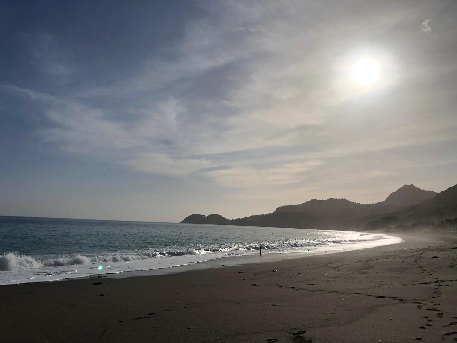Une plage avec un ciel dégagé et un soleil éclatant.