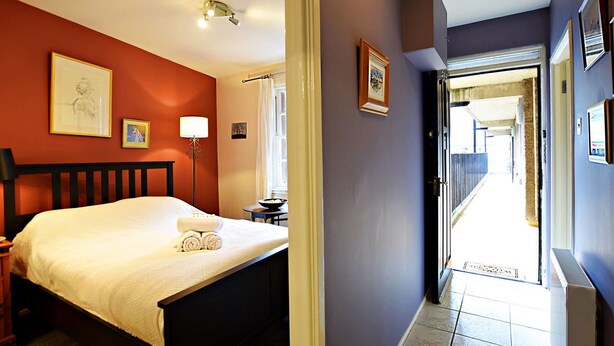 A hotel room with a bed, a bedside table, a lamp, and a window with curtains.