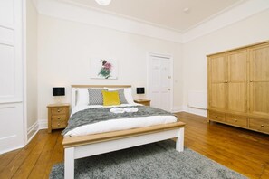 A bedroom with a bed, bedside tables, a wardrobe, and a door. - JOIVY Great Location! Heart of City Centre 3bed Apartment (Edinburgh)