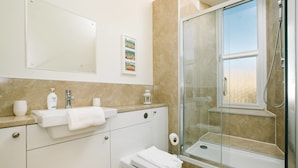 A modern bathroom with a glass shower enclosure, a sink with a towel, and a toilet. - JOIVY Great Location! Heart of City Centre 3bed Apartment (Edinburgh)