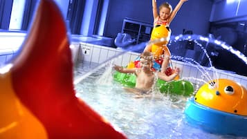 Ein Kind spielt in einer Wasserspielanlage mit aufblasbaren Spielsachen und einer Wasserrutsche.