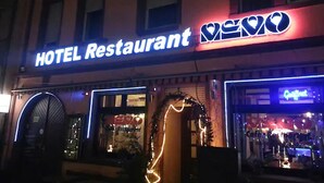 A hotel restaurant with a neon sign, a large window, and a visible entrance. - Hotel Restaurant Memo (Mannheim)