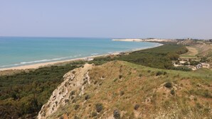 A coastal landscape with a beach, greenery, and buildings in the distance. - Casa Vacanza Villa Sole (Siculiana)