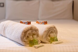 A neatly made bed with two rolled white towels, each with a bottle of lotion and a bar of soap. - JOIVY Location, Location! North Bank Street Luxury Apt (Edinburgh)