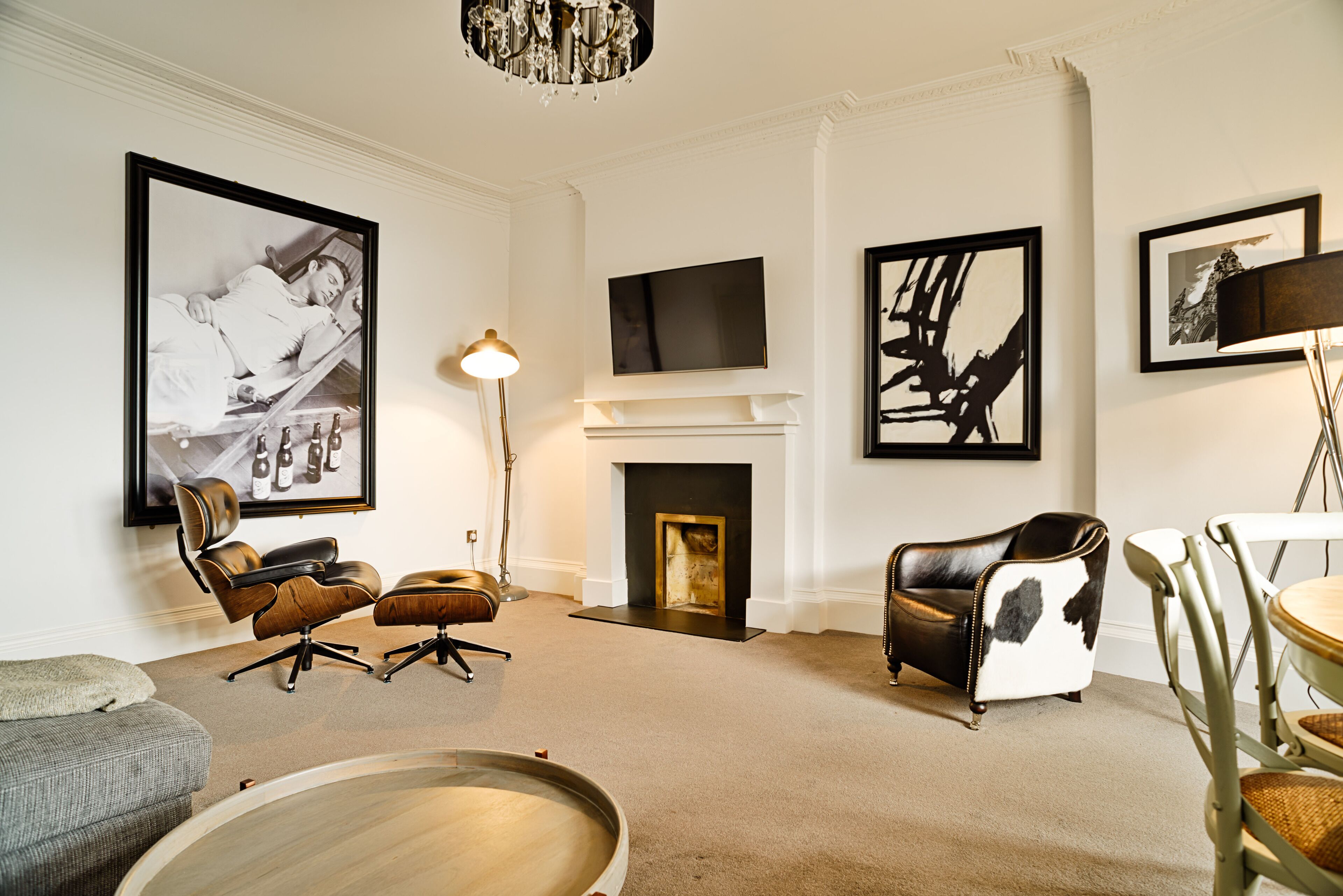 A modern living room with a fireplace, leather armchairs, a dining table, and artwork on the walls.