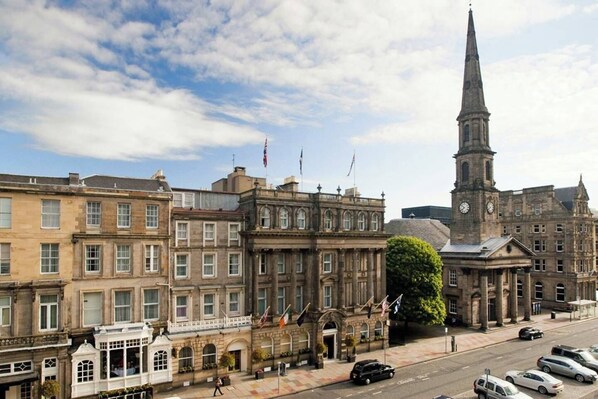 A historic building with a prominent clock tower, classic architecture, and flags.