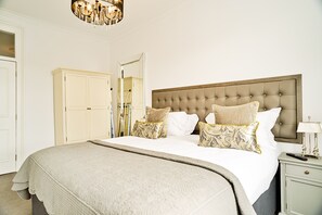 A bedroom with a large bed, a tufted headboard, and a nightstand with a lamp.