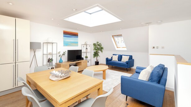 Ein modernes Wohnzimmer mit einem Holzesstisch, einem blauen Sofa und einem Fernseher.