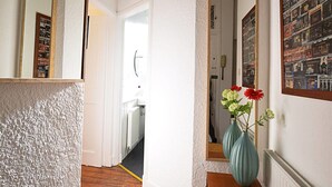 A hallway with a textured wall, a mirror, a door leading to another room, and a vase with flowers on a table. - JOIVY Bright New Town 2 bed Apt - 5 Mins to Princes St (Edinburgh)