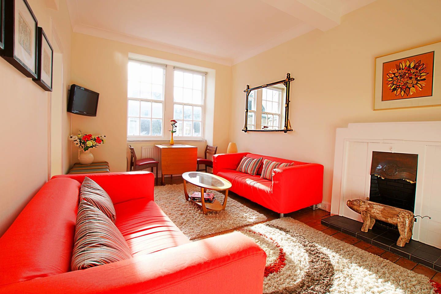 A living room with a red sofa, a coffee table, a fireplace, and a dog statue.