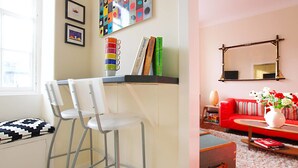 A room with a bar area, two white chairs, a red sofa, a mirror, and a vase with flowers. - JOIVY Bright New Town 2 bed Apt - 5 Mins to Princes St (Edinburgh)