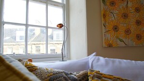 A bedroom with a bed, a window, and a painting of sunflowers. - JOIVY Bright New Town 2 bed Apt - 5 Mins to Princes St (Edinburgh)