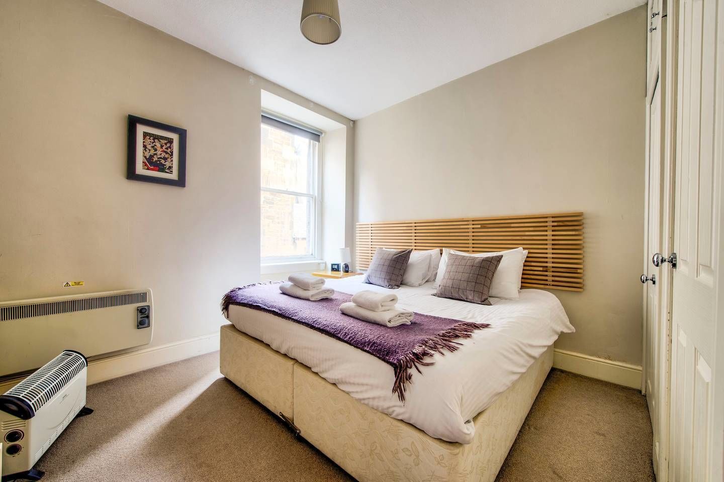 A bedroom with a bed, a window, a radiator, and a door.