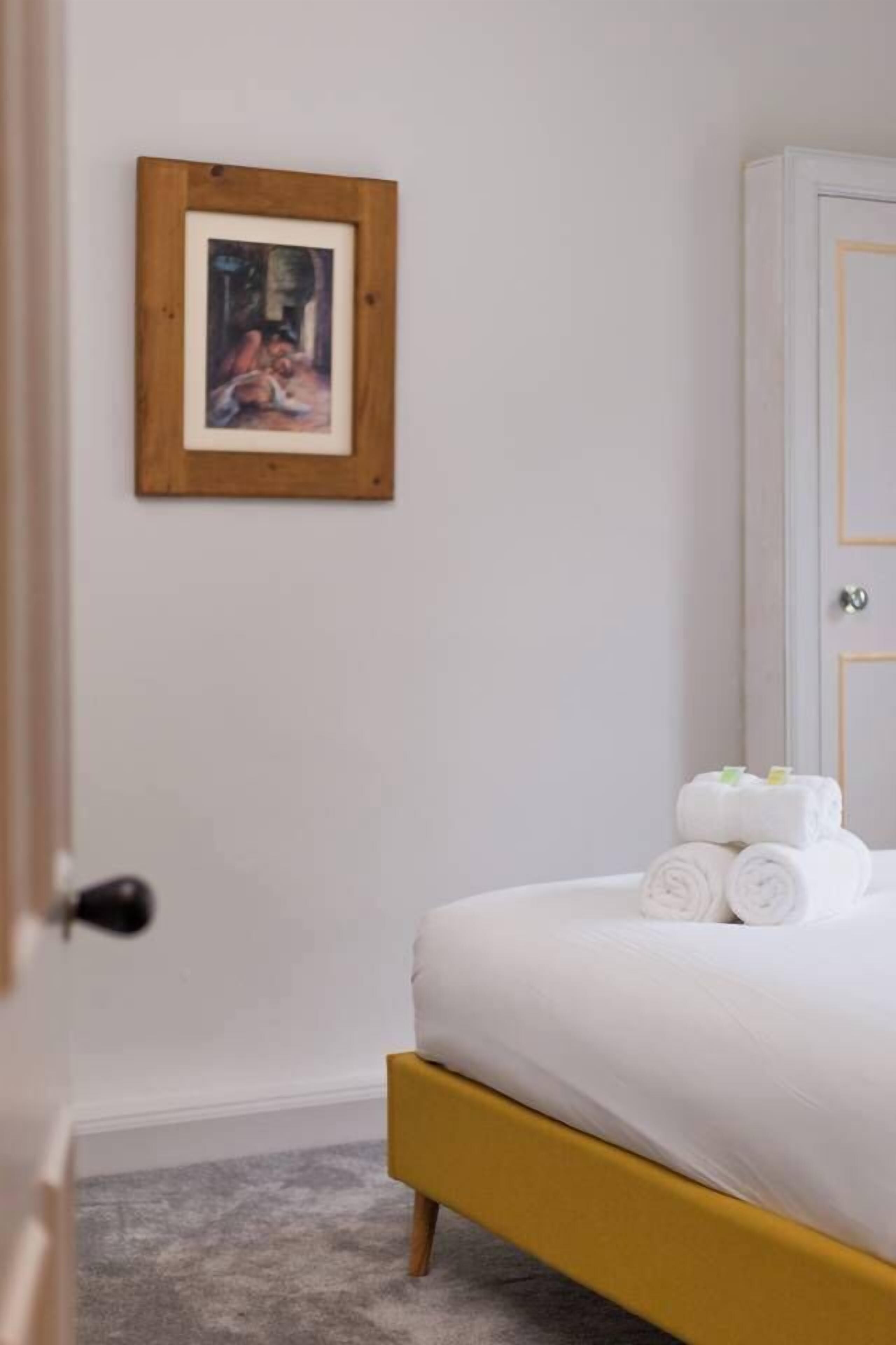 A bedroom with a bed, a framed picture on the wall, and a wardrobe.