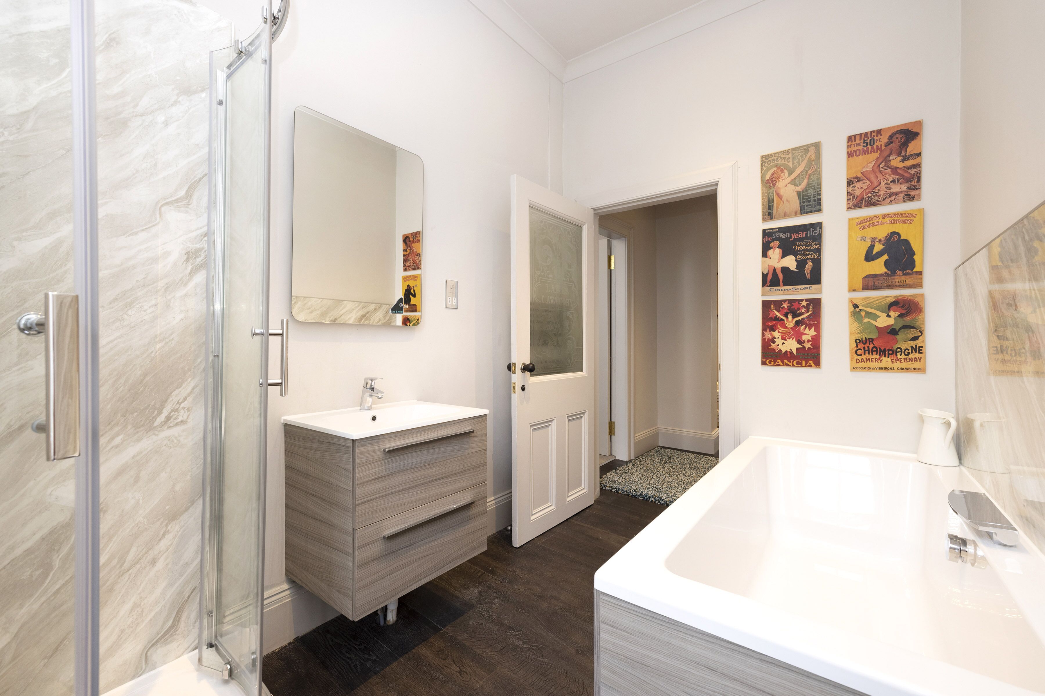 Un baño moderno con ducha de vidrio, lavamanos blanco y una bañera grande.