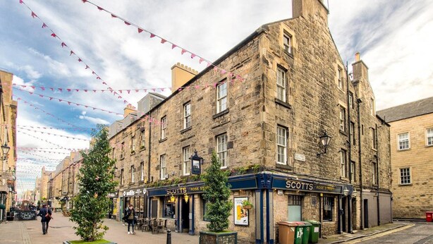 A historic stone building with a pub named 'Scott's Rose Street' on the ground floor. - JOIVY Perfect Location! - Stylish & Cosy Rose St Apt (Edinburgh)