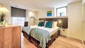 Ein modernes Schlafzimmer mit Bett, Nachttisch, Lampe und einem Fenster mit Blick.